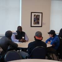 An alumnus talking with three students at the 30 Minute Mentors Event